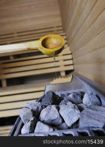 wooden luxury sauna indoor with hot stones and falling splashing water