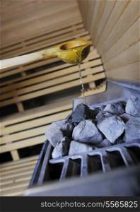 wooden luxury sauna indoor with hot stones and falling splashing water