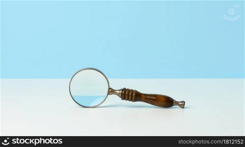wooden magnifier on a white background. The concept of uncertainty and the search for solutions, doubts