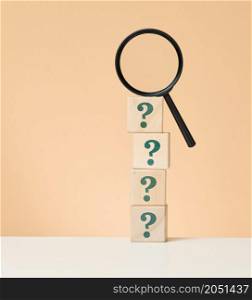 wooden magnifying glass and question marks. The concept of finding an answer to questions, truth and uncertainty. Answers on questions
