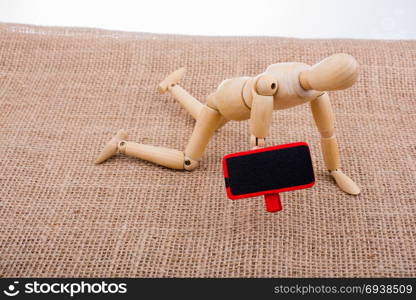 Wooden man on his knees with a notice board in his hand