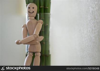 Wooden man standing at home and leaning on tree. People emotions concept. Drawn face