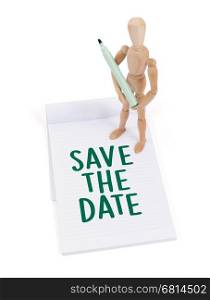 Wooden mannequin writing in a scrapbook - Save the date