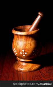Wooden mortar and pestle on dark wood background
