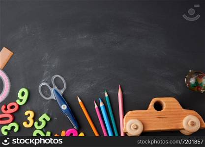 wooden multi-colored pencils, plastic numbers, scissors, wooden toy car on a black background, concept back to school, copy space
