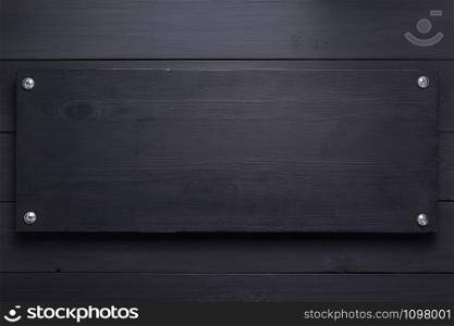 wooden nameplate at black background as texture surface with screws