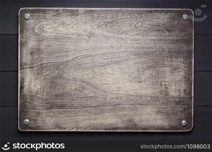 wooden nameplate at black background texture surface with screws