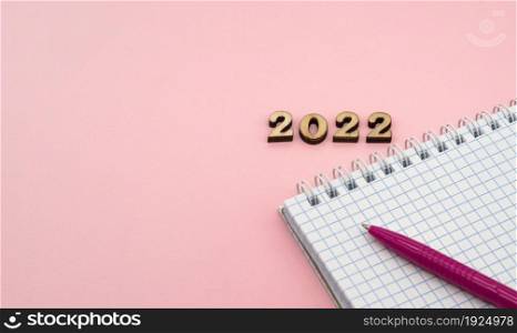 Wooden numbers 2022. Notepad on a spring. Notepad and Pen on Pink. Pink Pen. Spiral spiral checkered sheets.. Notepad and Pen on Pink. Wooden numbers 2022. Notepad on a spring. Pink Pen. Spiral spiral checkered sheets.