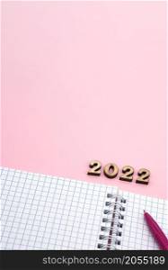 Wooden numbers 2022. Notepad on a spring. Notepad and Pen on Pink. Pink Pen. Spiral spiral checkered sheets. Vertically.. Notepad and Pen on Pink. Wooden numbers 2022. Notepad on a spring. Pink Pen. Spiral spiral checkered sheets.