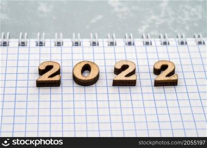 Wooden numbers date 2022. Notebook on the table. A blank sheet of paper.. Notebook on the table. Wooden numbers date 2022. A blank sheet of paper.