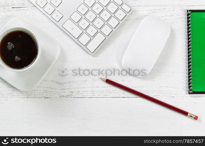 Wooden office table with computer, notepad, mouse, sharpen pencil, and black coffee. Top view angle with copy space.