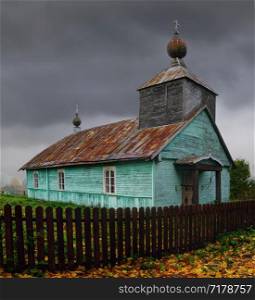 Wooden orthodox church against a cloudy sky, of forest village. Fall season. Rainy day.