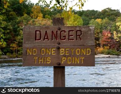 Wooden painted danger sign by rushing river