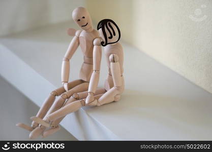 Wooden people sitting at home and hugging. People relationship concept. Drawn faces