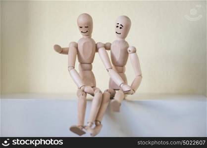 Wooden people sitting at home and hugging. People relationship concept. Drawn faces