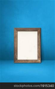 Wooden picture frame leaning on a blue wall. Blank mockup template. Wooden picture frame leaning on a blue wall
