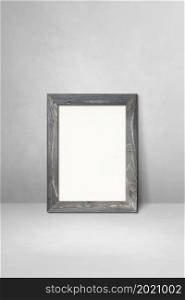Wooden picture frame leaning on a light grey wall. Blank mockup template. Wooden picture frame leaning on a light grey wall