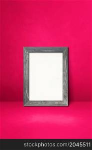 Wooden picture frame leaning on a pink wall. Blank mockup template. Wooden picture frame leaning on a pink wall