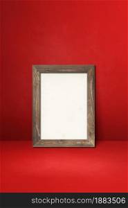 Wooden picture frame leaning on a red wall. Blank mockup template. Wooden picture frame leaning on a red wall