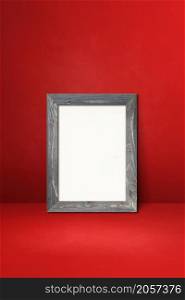 Wooden picture frame leaning on a red wall. Blank mockup template. Wooden picture frame leaning on a red wall