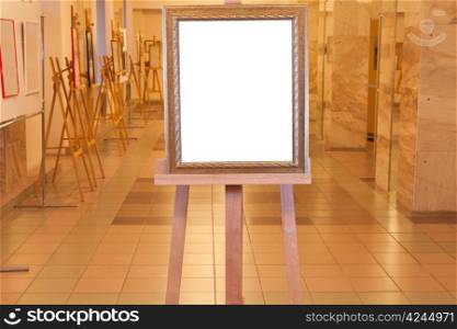 wooden picture frame with white cut out canvas on easel in art gallery
