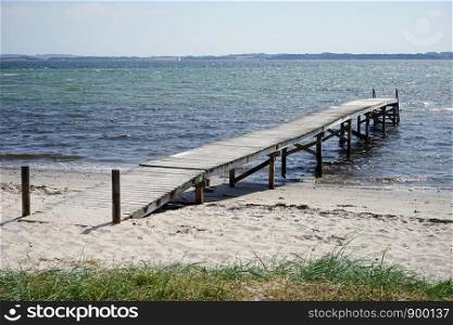 Wooden pier and sand beach on the Baltic sea coast of Denmsark