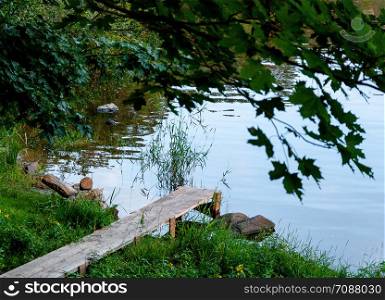 wooden pier from the planks near the river, made in the countryside. Wooden walkway near the river