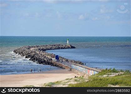 Wooden pier goes beyond sea horizon. people walk on pier