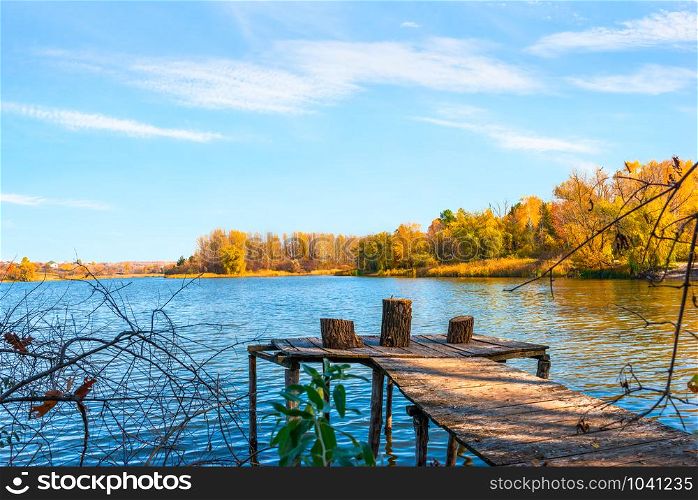 Wooden pier on river at sunny autumn day. Autumn and wooden pier