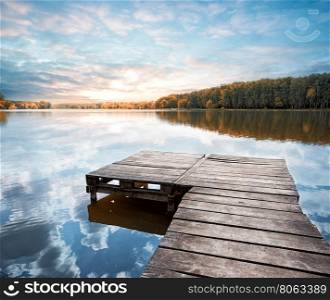 Wooden pier stretching into the lake at dawn. Wooden pier stretching into the lake
