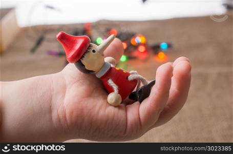 Wooden Pinocchio doll sitting in hand before lights