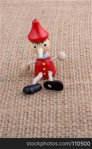 Wooden Pinocchio doll sitting on canvas background
