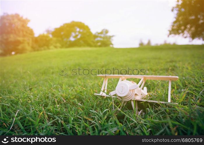 Wooden plane toy on green grass over blue sky with copyspace