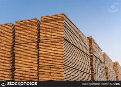 Wooden planks pile outside under the blue sky. Huge amount of timber planks. German wood factory storage