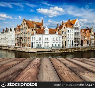 Wooden planks with European view of Bruges canal and old historic houses of medieval architecture in background. Brugge, Belgium. Wooden planks with Bruges canals in background