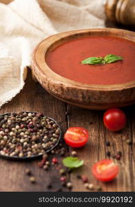 Wooden plate of creamy tomato soup with pepper and kitchen cloth on wooden board. with raw tomatoes. 