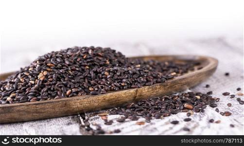 Wooden plate with black rice on old wooden background