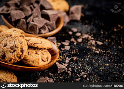 Wooden plate with cookies and pieces of milk chocolate. On a black background. High quality photo. Wooden plate with cookies and pieces of milk chocolate.