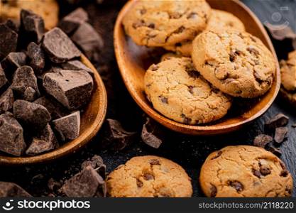 Wooden plate with cookies and pieces of milk chocolate. On a black background. High quality photo. Wooden plate with cookies and pieces of milk chocolate.