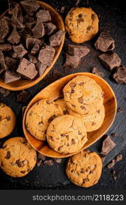 Wooden plate with cookies and pieces of milk chocolate. On a black background. High quality photo. Wooden plate with cookies and pieces of milk chocolate.