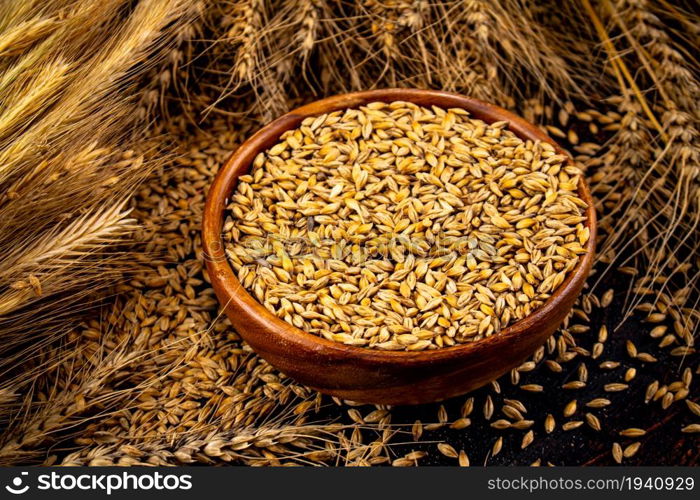 Wooden plate with rye grains and spikelets. On a dark background. . Wooden plate with rye grains and spikelets.