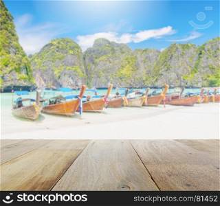 wooden platform with blurred long tail boat on white sand beach at maya bay, phi phi leh island, krabi-thailand