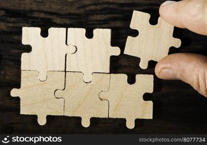 Wooden puzzle on dark wooden background.