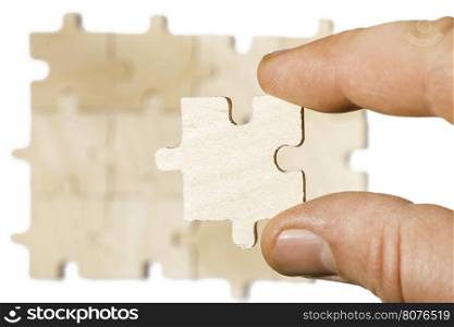 Wooden puzzle on white background. Hand holding puzzle piece. White isolated