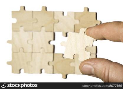 Wooden puzzle on white background. . Hand holding puzzle piece. White isolated