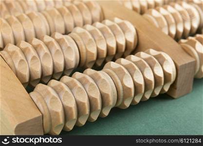 Wooden roller massage tool for feet on a green background