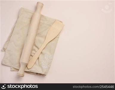 Wooden rolling pin for rolling dough on a beige background, top view. Copy space