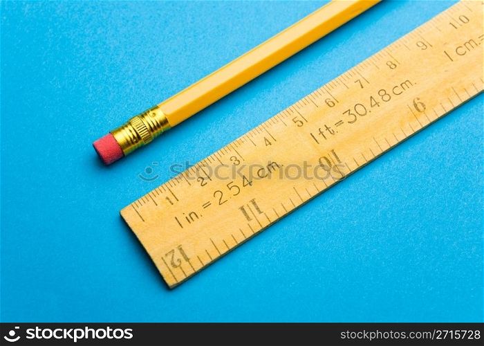 Wooden ruler and pencil laying on blue background