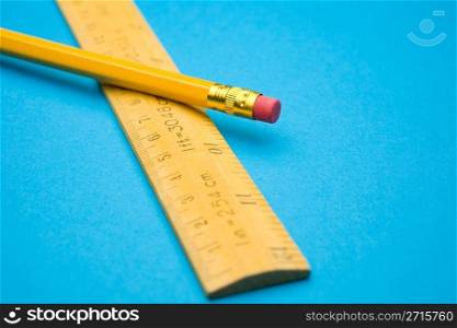 Wooden ruler and pencil on a blue background