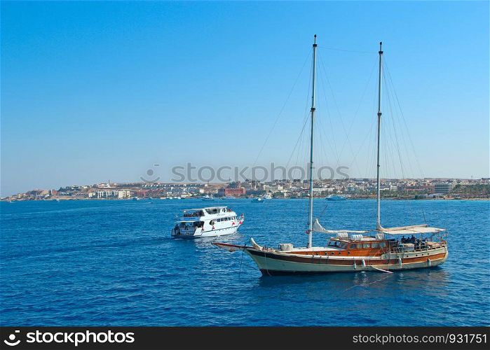 Wooden schooner on Red sea and touristic ship. Cruise ship and old frigate on Red Sea. Mass tourism on sea. Wooden schooner on Red sea and touristic ship
